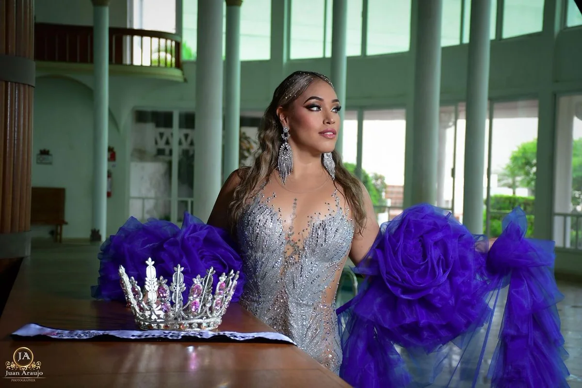 Gabriela Salazar con vestido de gala y detalles violetas junto a una corona
